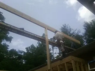 Carpenter setting a ridge beam over a new addition frame — Ice Dam Removal by Roofing Brothers in Davenport Center
