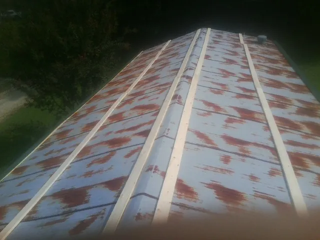 Rusted metal roof panels with new wood purlins before replacement — Storm Damage Roof Repair in Davenport Center by Roofing Brothers