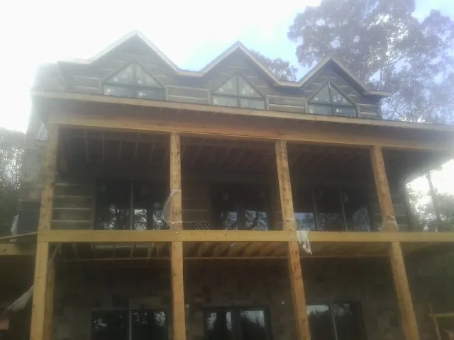 Dormers and porch framing on a large log home under construction — Roof Coating work by our crew in Davenport Center