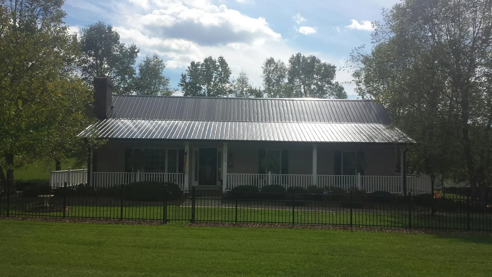 Gray metal roof on a brick ranch with a full width front porch — Gutter Guard Installation work by our crew in Davenport Center