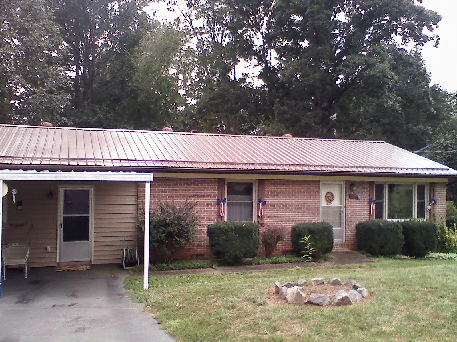 Bronze metal roof and carport on a brick ranch home — Roof Repair work by our crew in Davenport Center