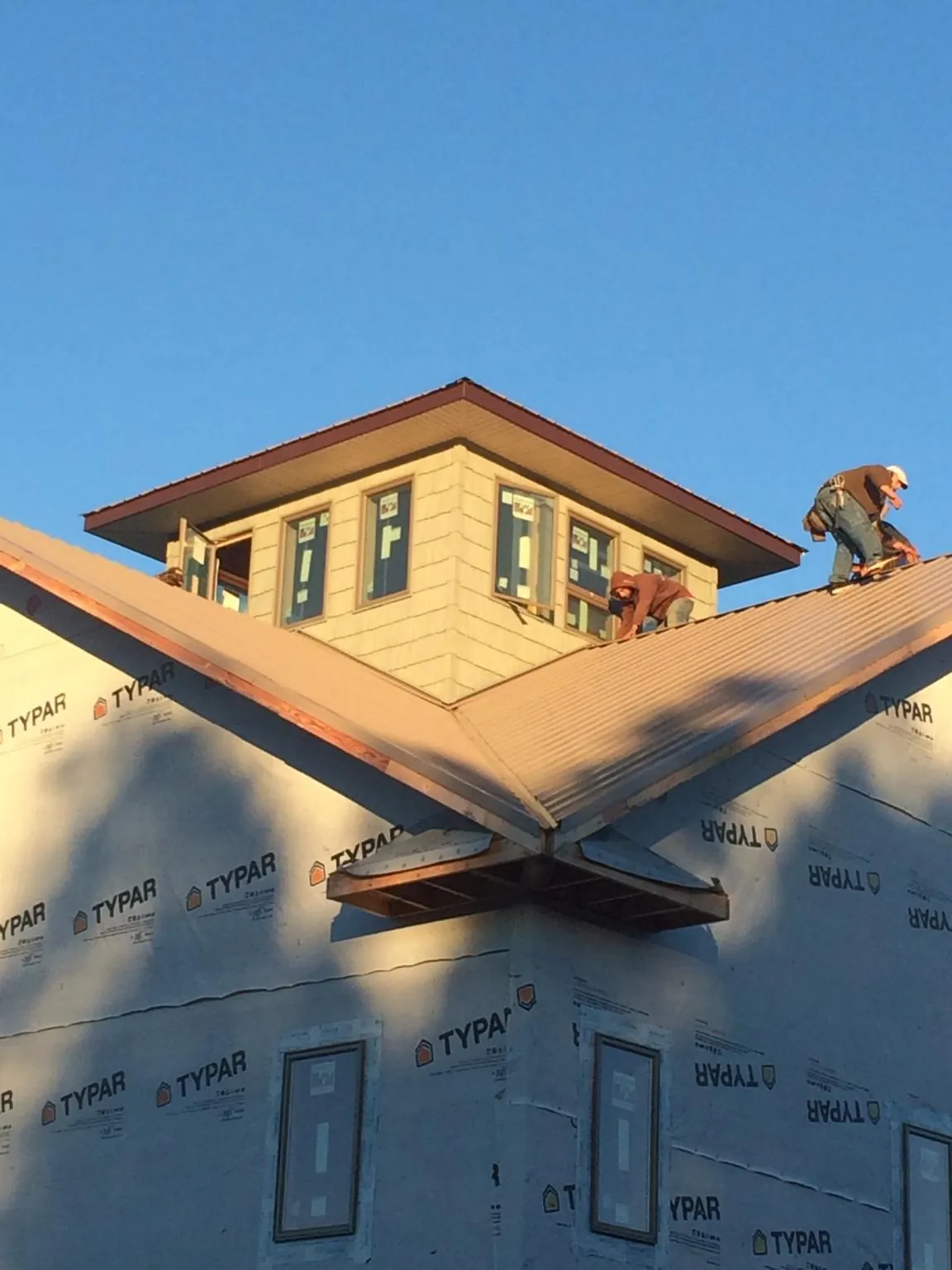 Roofers working around a rooftop cupola on a new metal roof at sunset — Roof Waterproofing in Davenport Center by Roofing Brothers